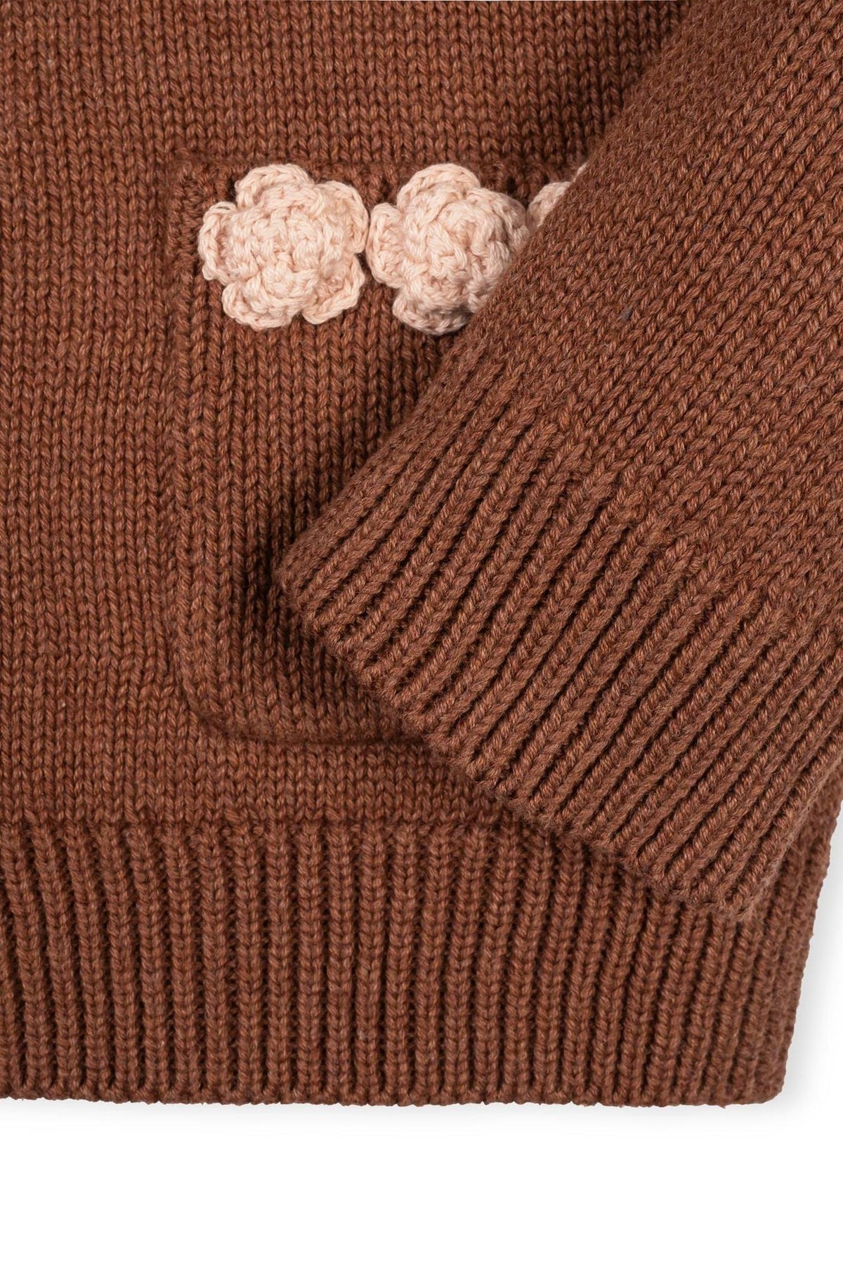 Close-up of a cinnamon-colored organic cotton cardigan featuring a textured knit and a decorative rosette pocket. The cozy design is perfect for toddlers and girls, emphasizing comfort and style.