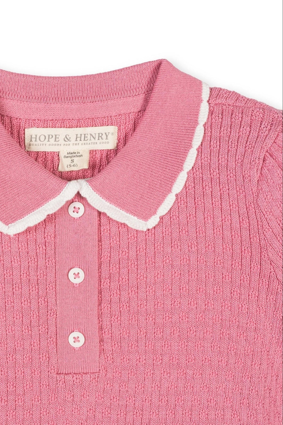 A close-up of a pink organic cotton sweater polo featuring a textured knit, a white-trimmed peter pan collar, and a henley button placket. Ideal for sustainable fashion lovers.