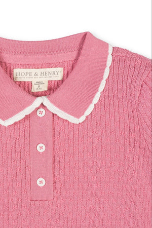 A close-up of a pink organic cotton sweater polo featuring a textured knit, a white-trimmed peter pan collar, and a henley button placket. Ideal for sustainable fashion lovers.