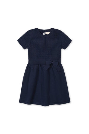 Navy short sleeve cable knit sweater dress featuring a textured bodice and a bow detail at the waist, crafted from 100% organic cotton for toddler and girls’ comfort and style.