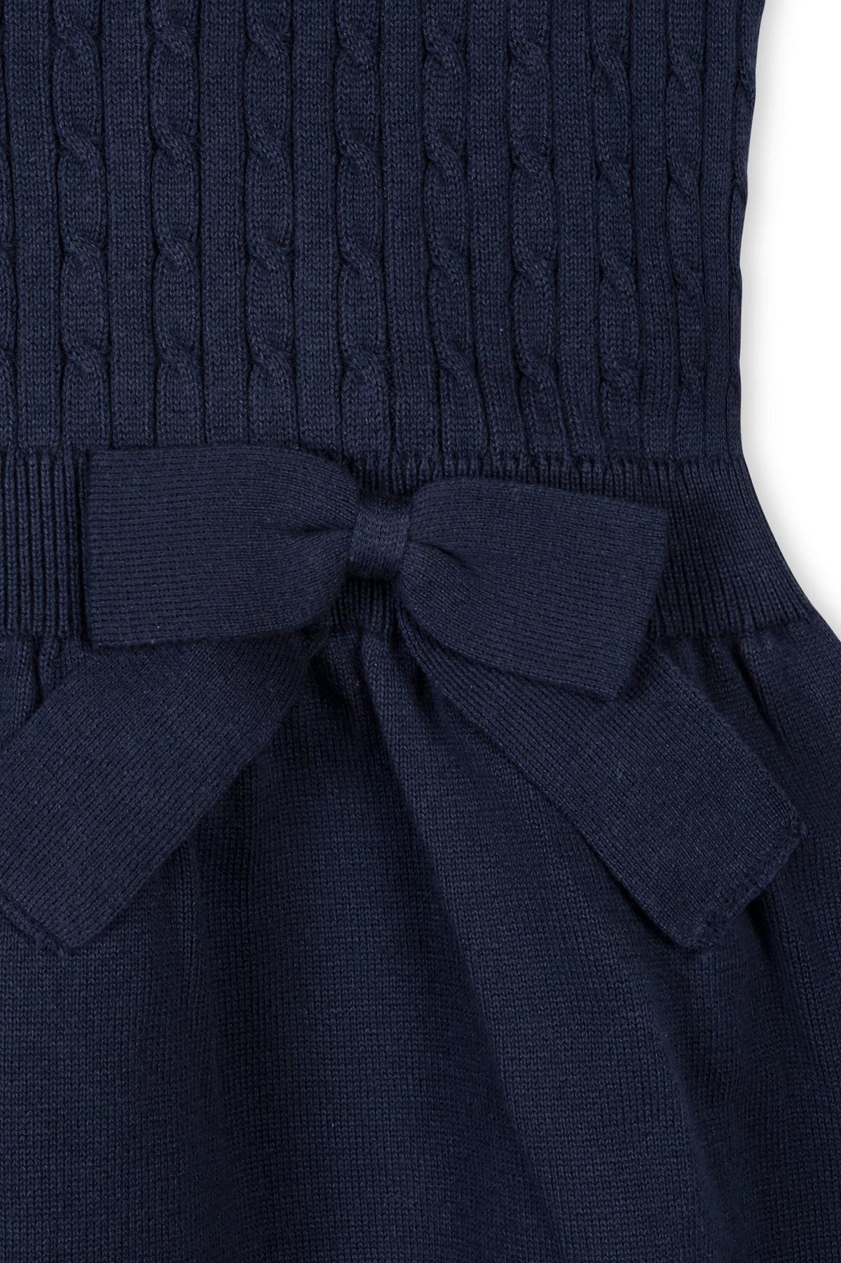 Close-up image of a navy blue cable knit sweater dress featuring a textured bodice and a bow detail at the waist, made from 100% GOTS Certified organic cotton for comfort.