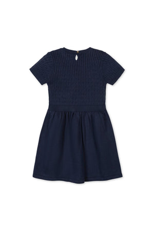 Back view of a navy blue short sleeve sweater dress featuring a textured cable knit bodice and a flared skirt. Made from 100% GOTS certified organic cotton for comfort.