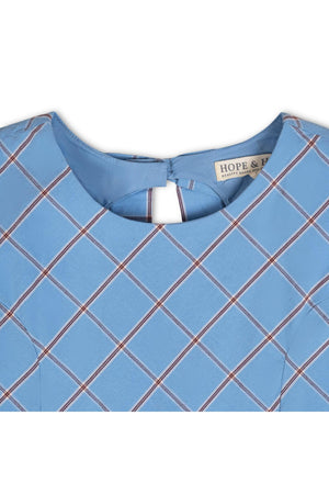 Close-up of a blue plaid dress featuring a round neckline and a button back closure, made from organic cotton.