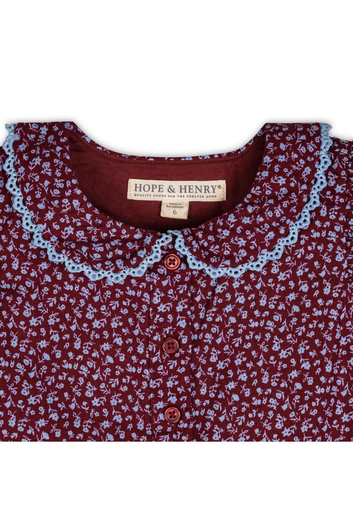 A close-up of a wine-colored dress featuring a Peter Pan collar with delicate blue crochet trim. The fabric showcases a floral pattern, and the brand label reads Hope & Henry.
