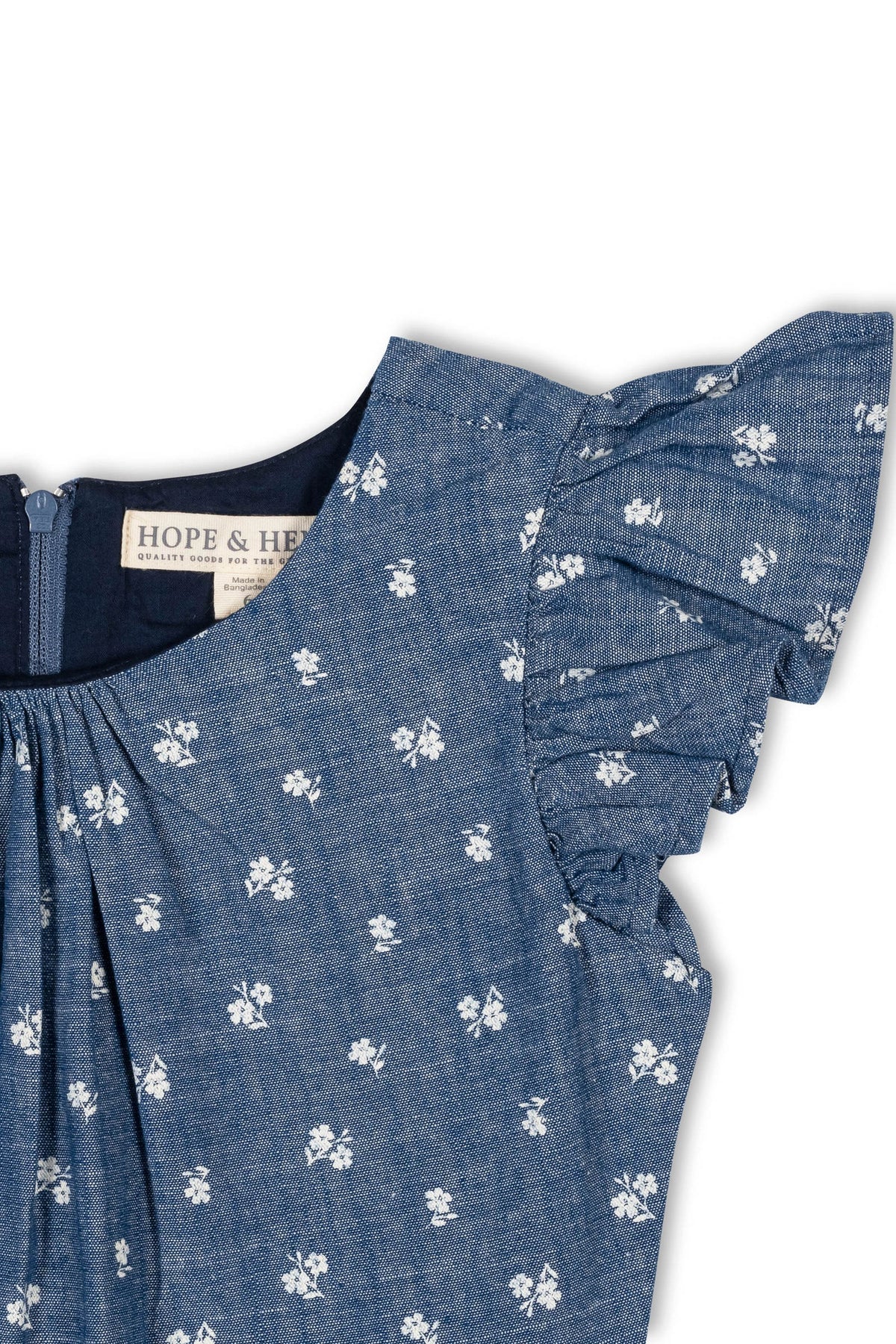 Close-up of a chambray dress featuring delicate white floral patterns and ruffle sleeves. The dress is made from soft organic cotton, designed for toddlers and girls, offering a stylish, comfortable.