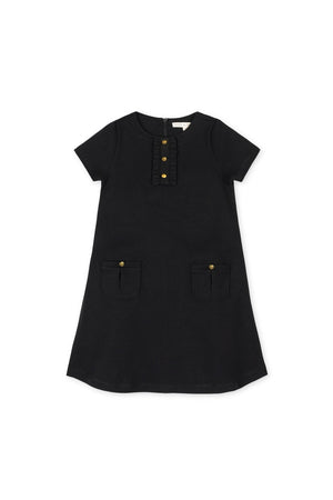 A black A-line dress featuring short sleeves, a ruffle placket, and button details, with two front pockets. Made from organic cotton, its perfect for toddlers and girls.