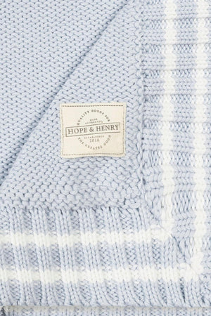 A pale blue cable knit baby blanket features a classic stripe trim and a woven label reading Hope & Henry.