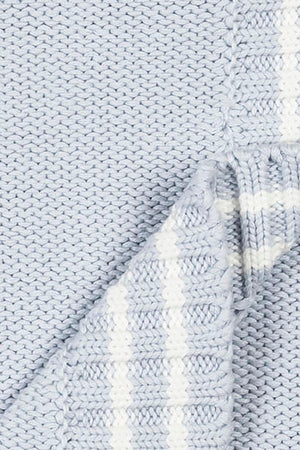 Close-up of a pale blue organic cotton cable knit baby blanket featuring a chunky purl stitch and classic white stripe trim, showcasing its soft texture and sustainable material.