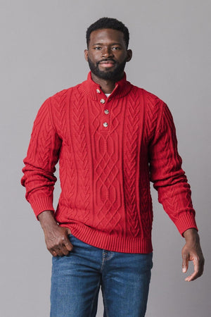 A man stands confidently in a vibrant red mock neck cable sweater made of soft organic cotton.