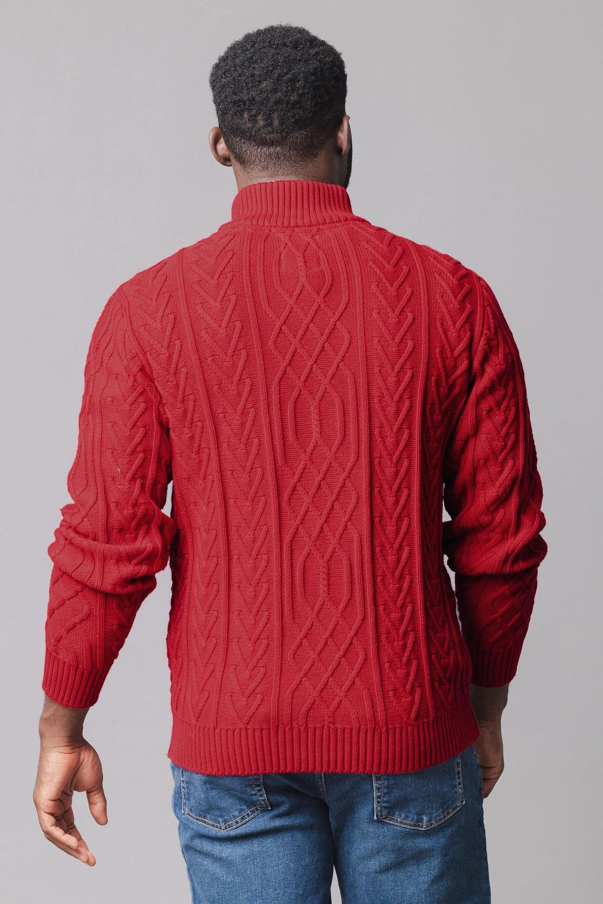 A man is shown from the back wearing a vibrant red mock neck cable sweater made of soft organic cotton.