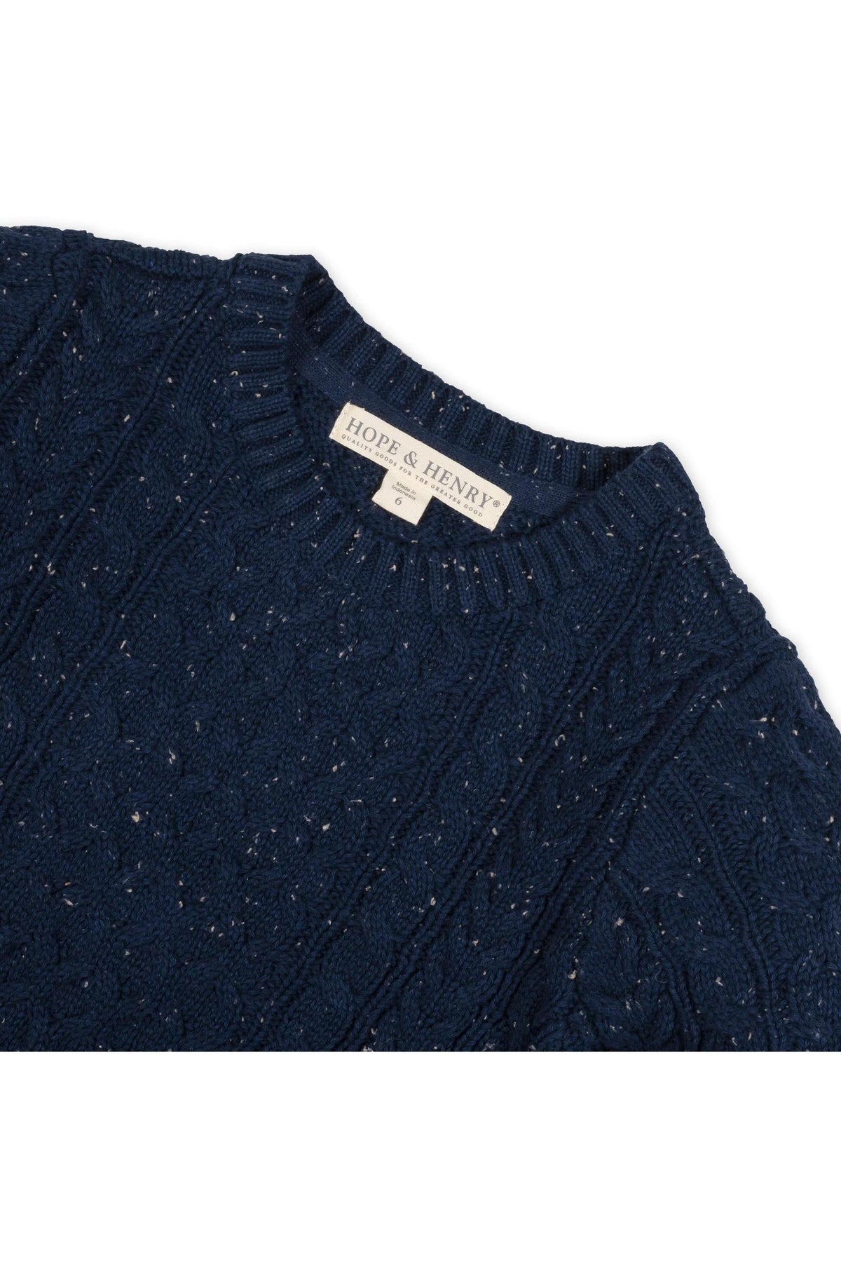 A close-up of a navy blue cable knit fisherman sweater from Hope & Henry, showcasing its textured pattern and organic cotton material. The label is visible at the neckline.