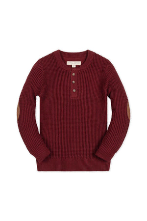 A cozy oxblood waffle sweater henley with faux suede elbow patches, featuring a button closure and ribbed cuffs. Made from soft organic cotton, perfect for ages 2T-18.