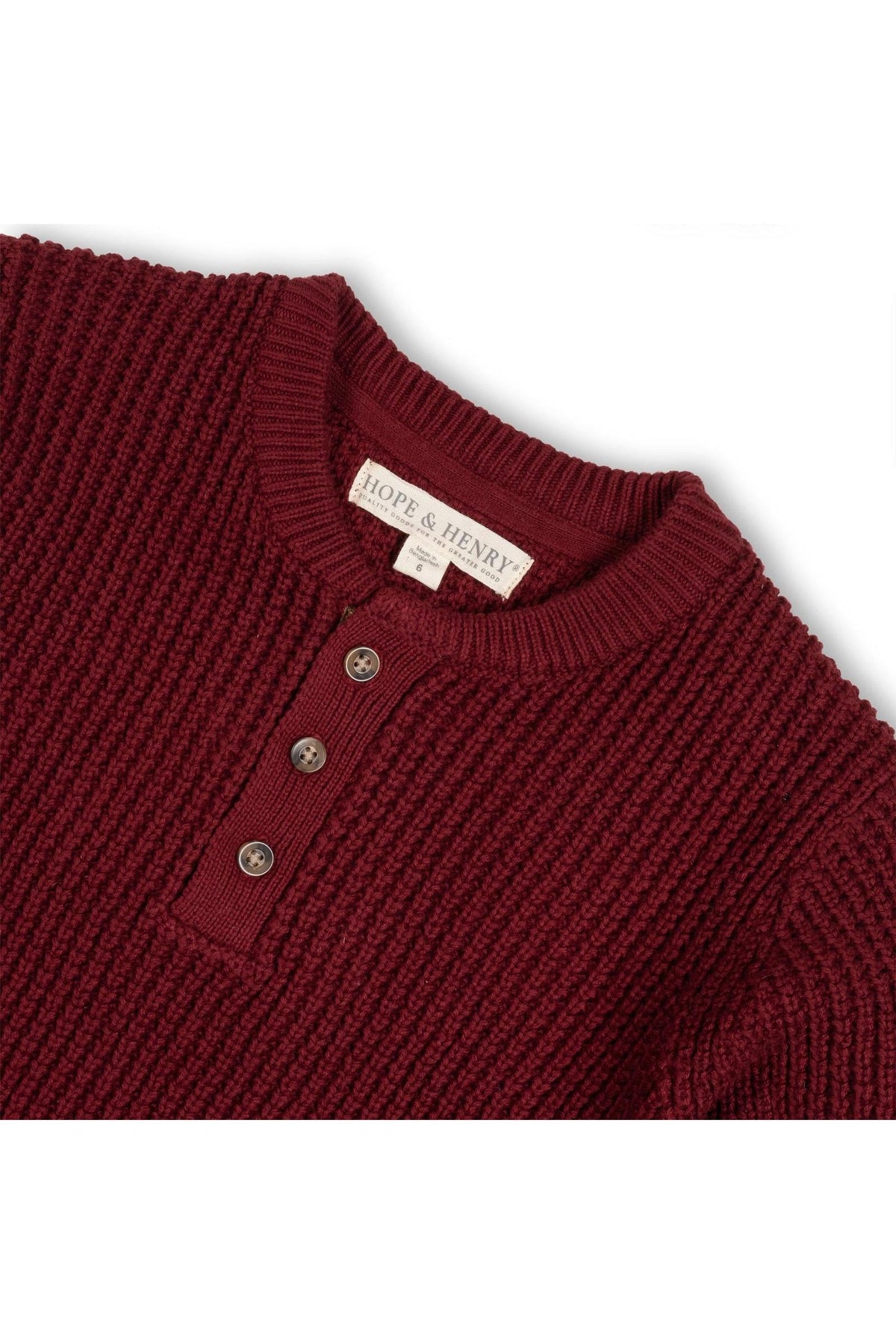 A close-up of a burgundy waffle-knit sweater henley featuring a three-button placket and ribbed collar. Made from soft organic cotton, it is designed for comfort and style.