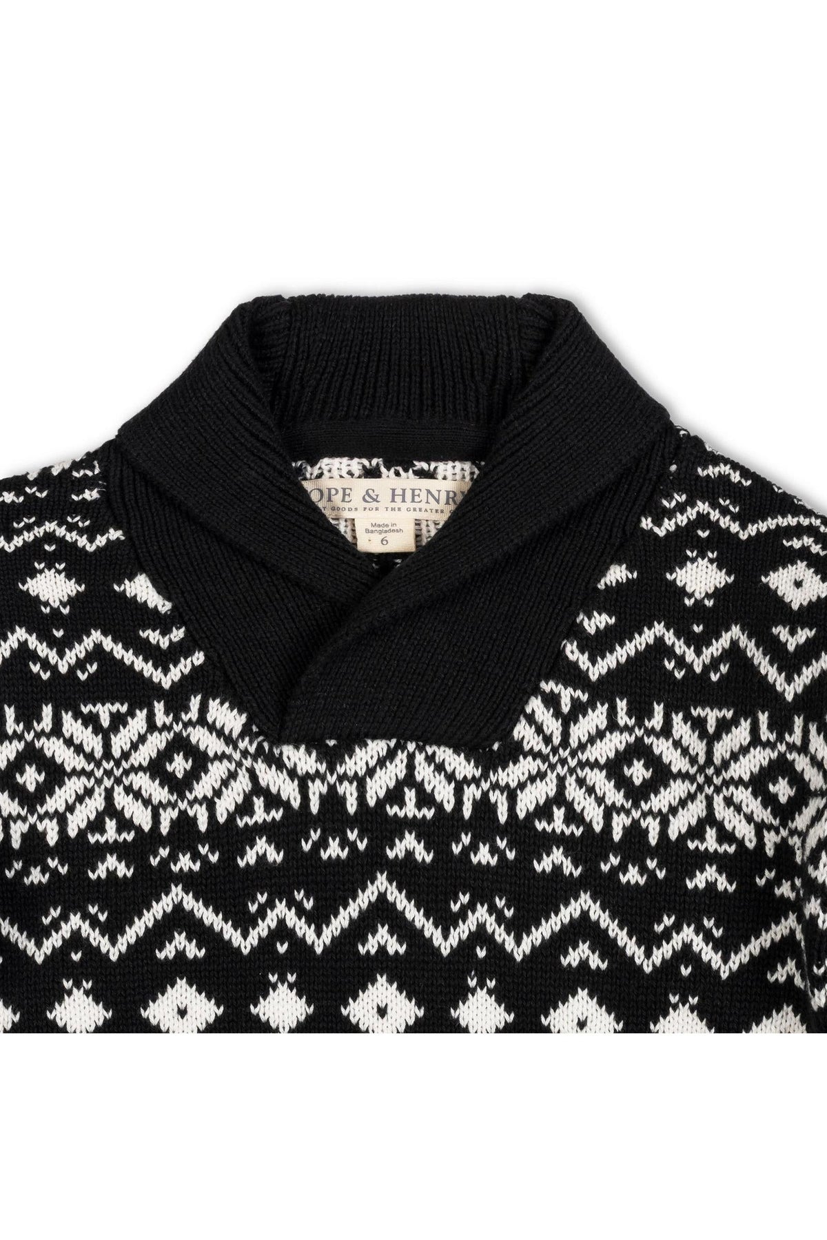 A close-up view of a black and white organic cotton shawl collar sweater featuring a snowflake pattern. The sweater is labeled with the brand name Hope & Henry.
