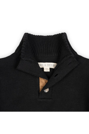 Close-up of a black organic cotton mock neck sweater featuring a ribbed collar and faux suede button placket. The brand label Hope & Henry is visible inside the collar.