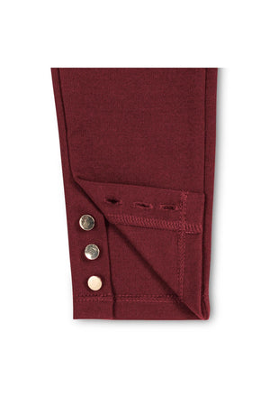 Close-up image of the hem of a burgundy ponte pant featuring three gold shank buttons at the ankle. The fabric is thick and textured, ideal for toddlers and girls.