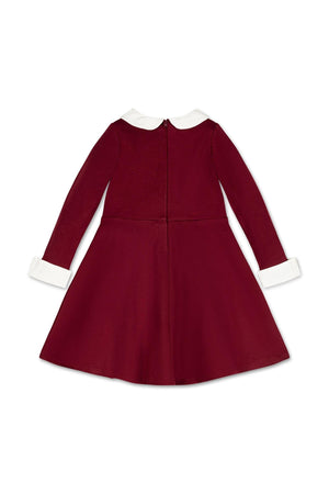 A back view of a toddler and girls dress in oxblood, featuring long sleeves, a white Peter Pan collar, and cuffs. The dress is made from comfortable ponte knit fabric.