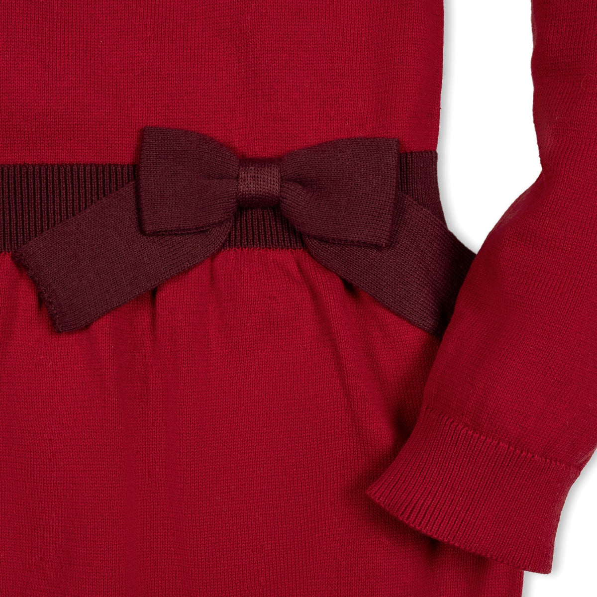 Close-up of a red organic cotton skater sweater dress featuring a textured bodice and a decorative bow at the waist, perfect for toddlers and girls.