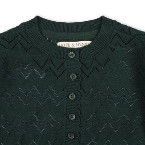 Close-up of a deep green organic cotton henley sweater featuring a scalloped placket and textured zigzag pattern, with button closures and the brand label Hope & Henry visible.