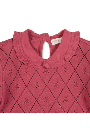 Close-up of a rosewood-colored organic cotton sweater featuring a delicate diamond pattern, a ruffled Peter Pan collar, and a keyhole closure at the back neck for easy dressing.
