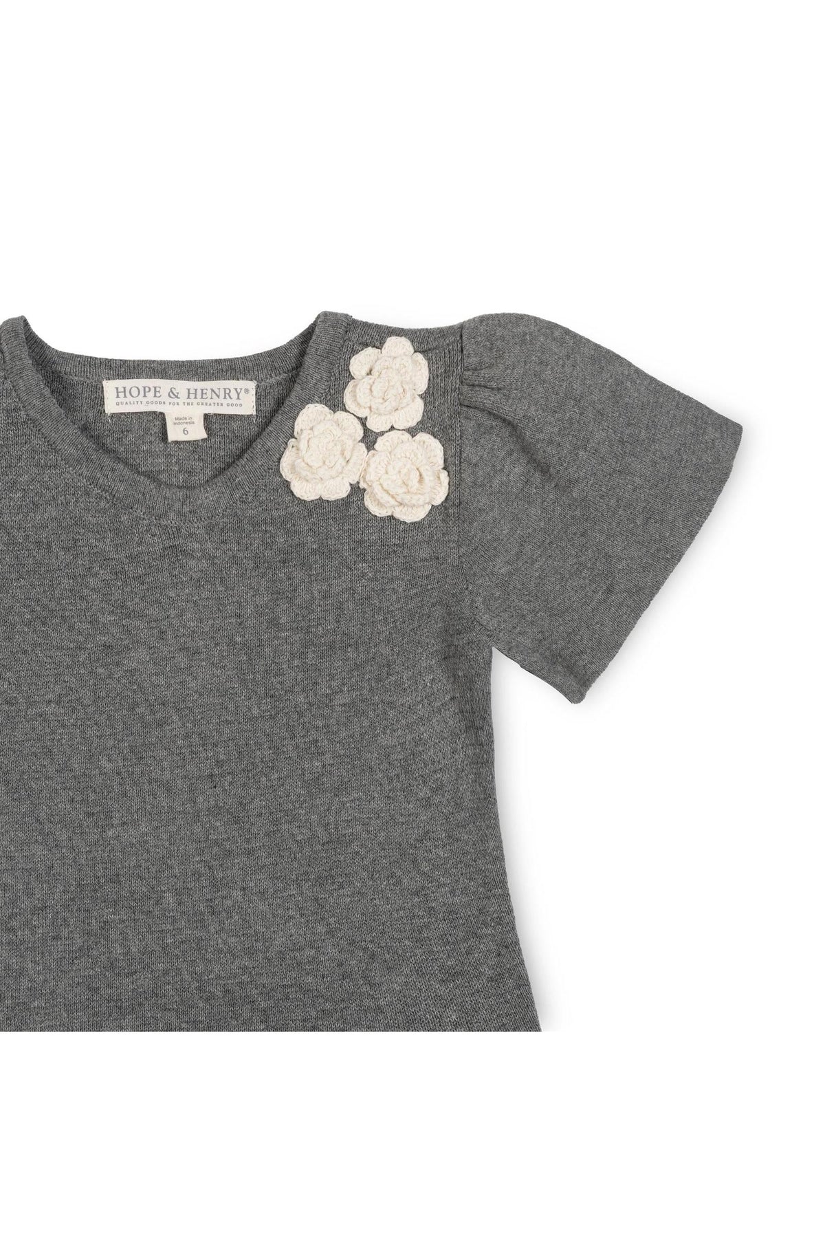 Close-up of a dark gray sweater featuring soft organic cotton fabric. The dress has decorative rosettes at the neckline, adding a charming detail suitable for toddlers and girls.
