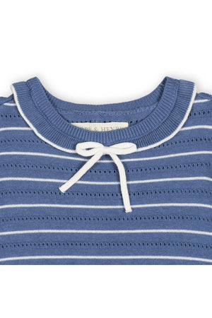 Close-up of a denim blue striped sweater dress featuring a ruffle collar and a white bow tie. The organic cotton material is soft and breathable, ideal for toddlers and girls.
