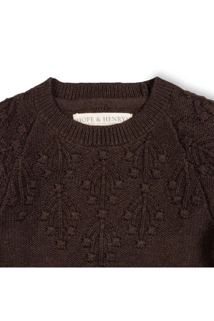 Close-up of a chocolate heather organic cotton sweater featuring a decorative stitch pattern on the shoulders. The label reads Hope & Henry, highlighting its sustainable attributes for toddlers and girls.