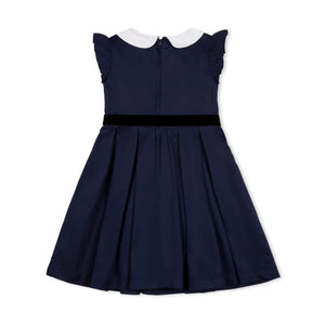 A navy organic cotton dress features a woven Peter Pan collar and flutter sleeves, with a black waist sash and bow.
