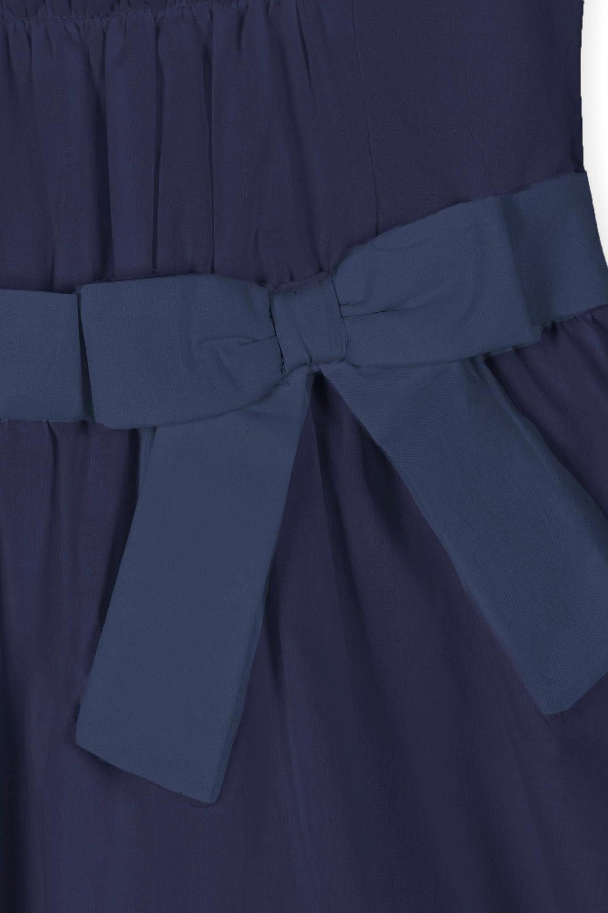 Close-up image of a navy blue dress featuring a shirred bodice and a waist sash with a bow.