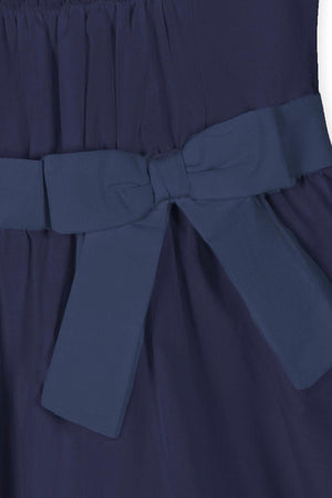 Close-up image of a navy blue dress featuring a shirred bodice and a waist sash with a bow.
