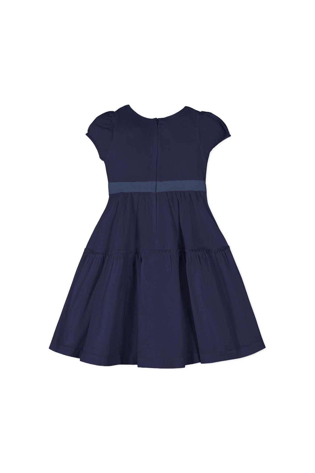 Navy organic cotton puff sleeve dress featuring a tiered skirt and waist sash. The back has a zipper for easy dressing, perfect for toddlers and girls at special occasions.