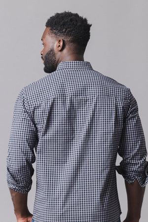 A man is seen from behind, wearing a black gingham organic cotton poplin shirt with long sleeves.