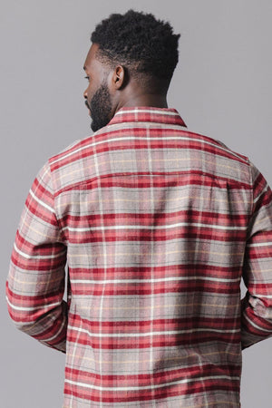 A man is wearing a cozy, organic cotton flannel shirt in rosy taupe plaid. The shirt features a button-down style and is seen from the back against a neutral background.