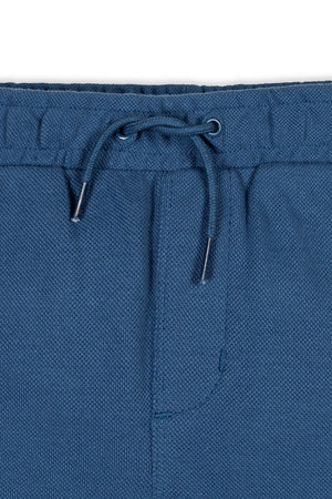 Close-up of stone blue organic cotton pique pull-on shorts featuring an elastic waistband and adjustable drawstring. The lightweight fabric is perfect for comfortable, everyday wear for children.