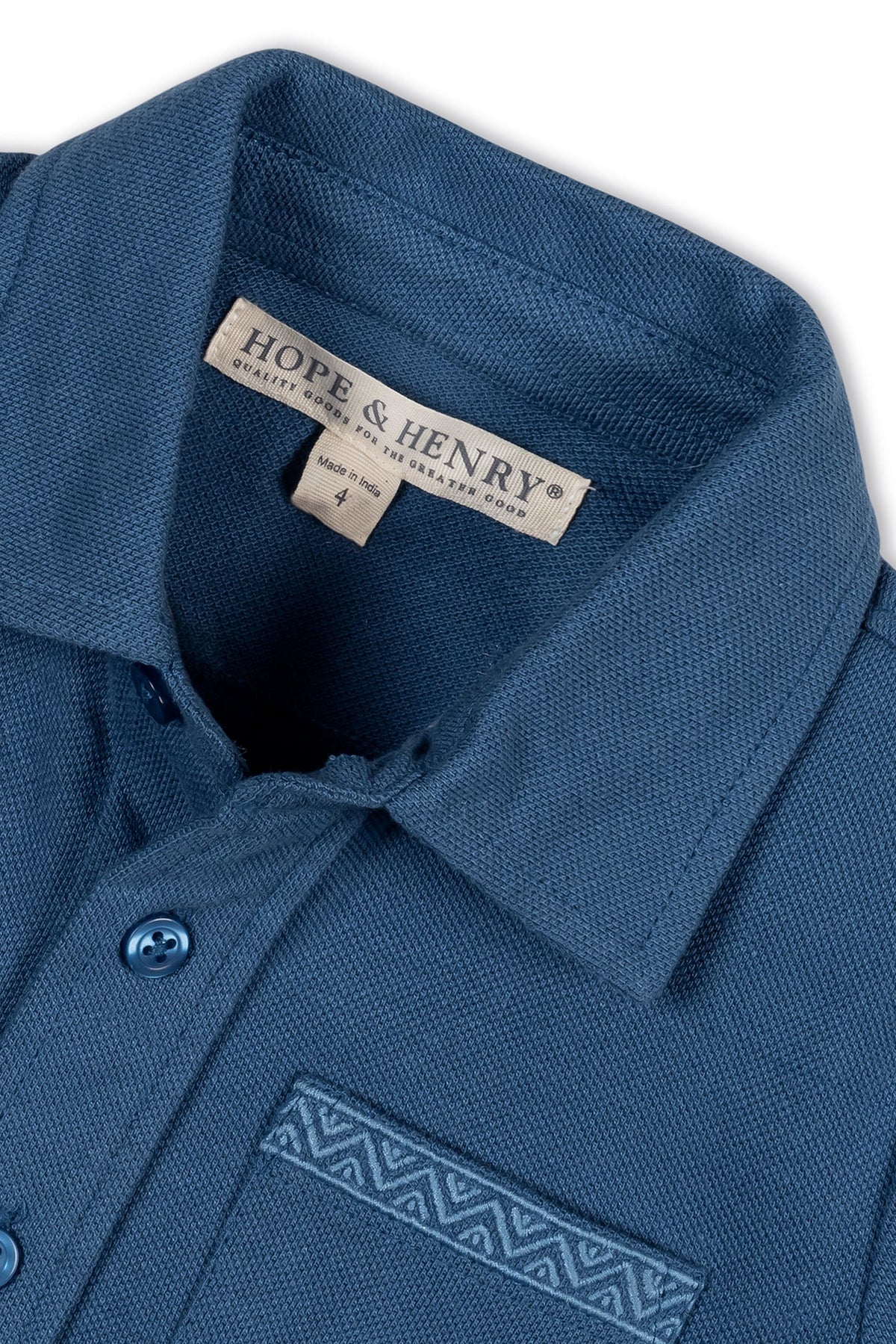 Close-up of a stone blue organic cotton short sleeve pique button-down shirt by Hope & Henry, featuring a textured fabric and a decorative pocket detail, suitable for children ages 2T-12.
