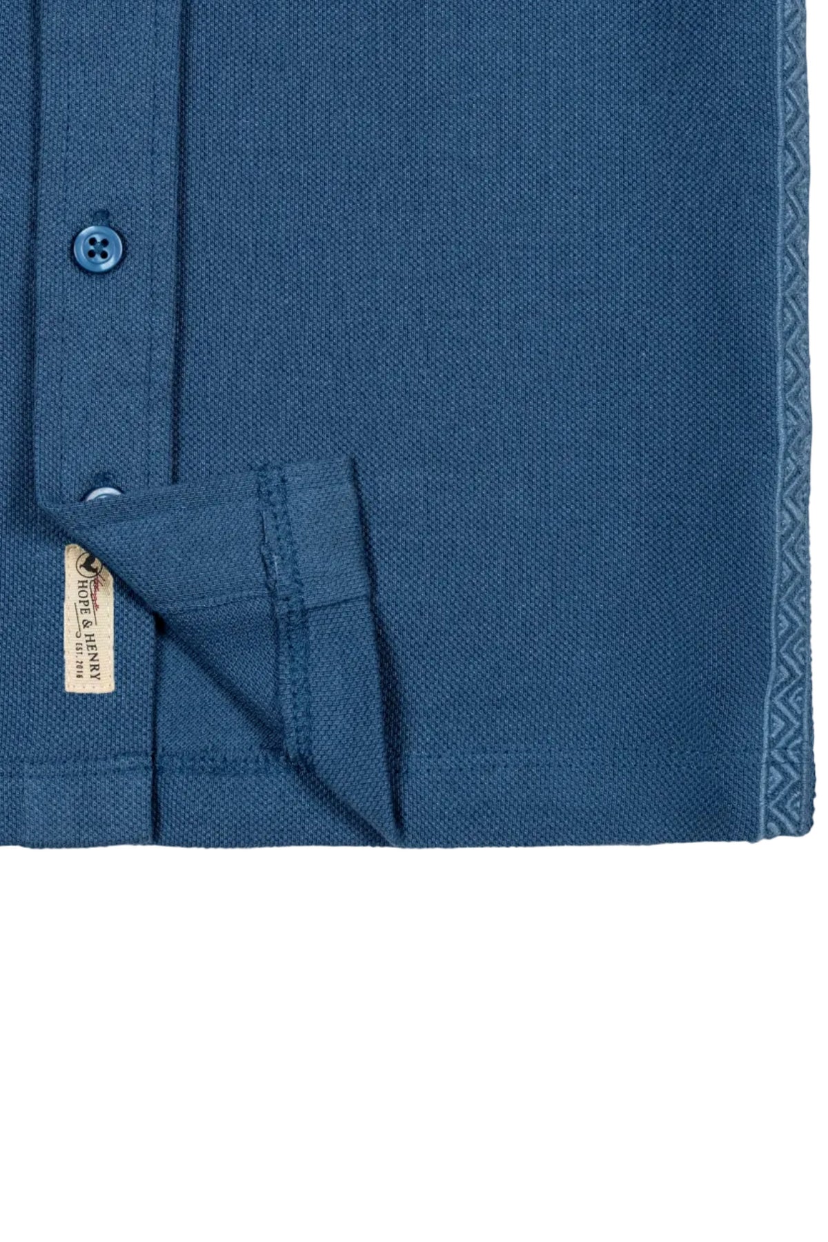 Close-up of a stone blue organic cotton short sleeve pique button down shirt, featuring a button placket and decorative stitching along the hem. Ideal for toddlers and kids.