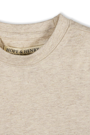 Close-up of a soft, oatmeal-colored organic cotton short sleeve Henley tee from Hope & Henry, featuring a classic neckline and a label showcasing its sustainable attributes. Perfect for kids.