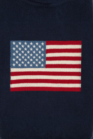 Close-up of a navy blue sweater featuring an American flag intarsia design with embroidered stars. Made from soft, organic cotton, it’s perfect for family gatherings and everyday wear.