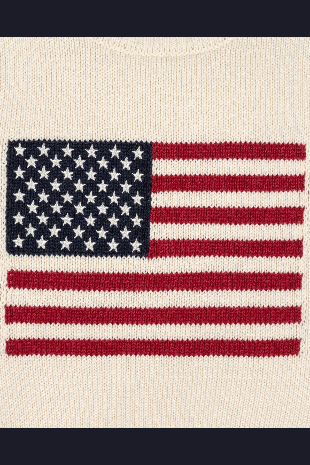 An ivory sweater features a knitted American flag design in red, white, and blue. Crafted from soft, organic cotton, its ideal for kids patriotic celebrations and family matching outfits.