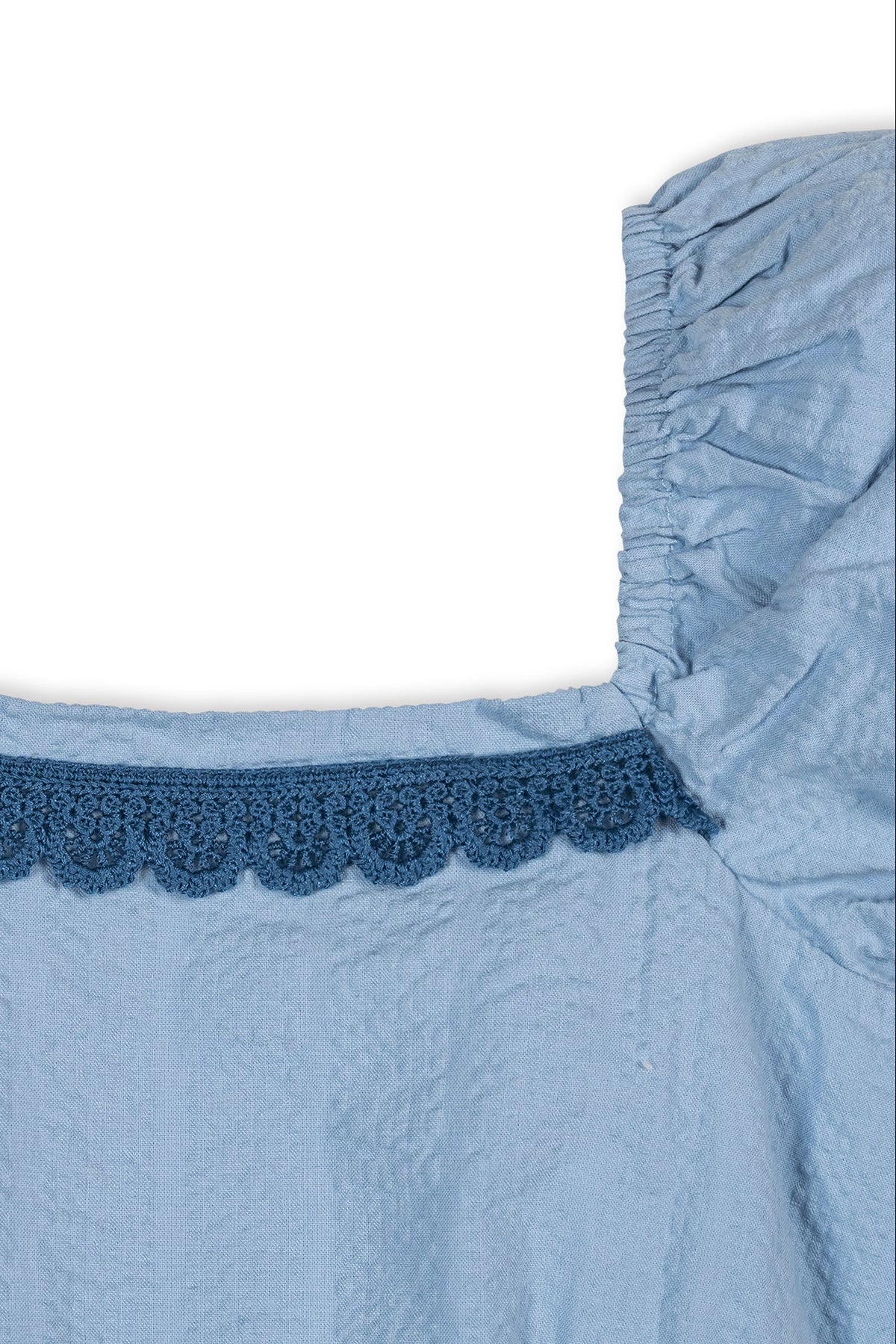 Close-up of a blue organic cotton fabric featuring puff sleeves and delicate crochet trim along the neckline. The textured seersucker material adds a charming touch for toddlers and kids.