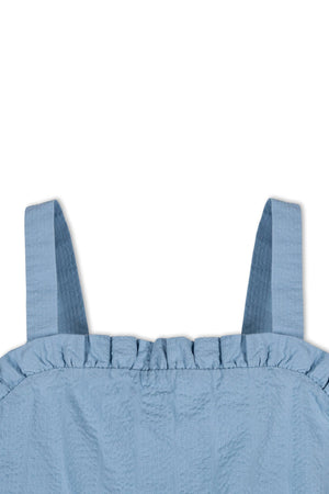Close-up of the blue seersucker dress by Hope & Henry, featuring ruffled edges and adjustable straps. Made from organic cotton, it is designed for children aged 2T-12.