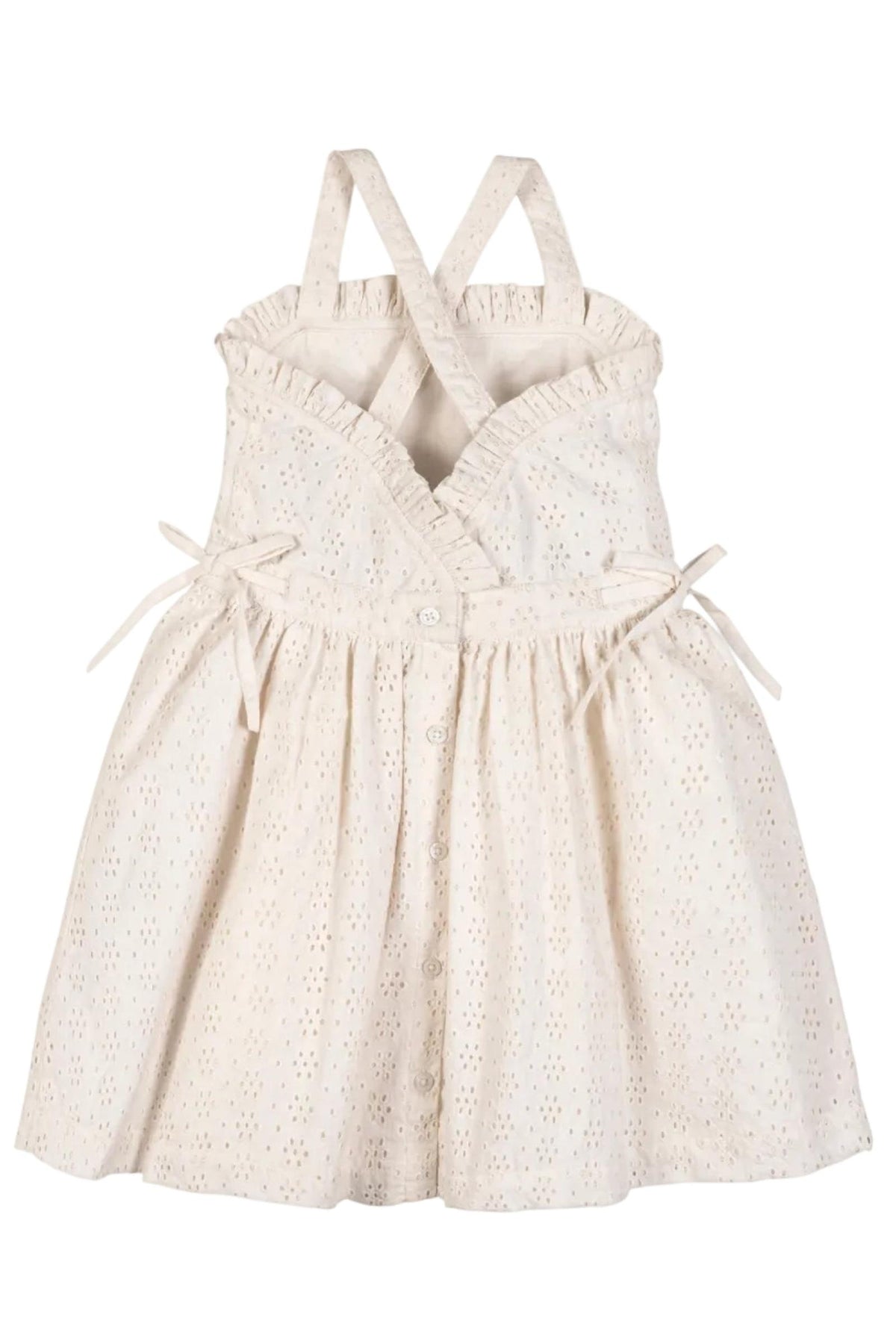 A light beige organic cotton dress features ruffle edges, cross-back straps, and a button closure down the center. This airy eyelet dress is perfect for summer adventures.