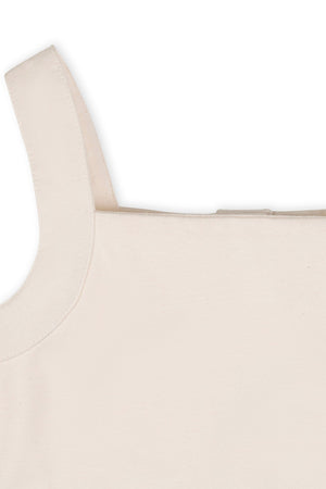Close-up view of the back of a cream-colored organic cotton tank sundress, showcasing the wide straps and button closure. The soft fabric highlights its eco-friendly and sustainable attributes.