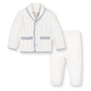 A cozy, snow white baby cardigan and matching pants made from soft, GOTS certified organic cotton. The classic cable knit design features blue trim, perfect for keeping little ones comfortable.
