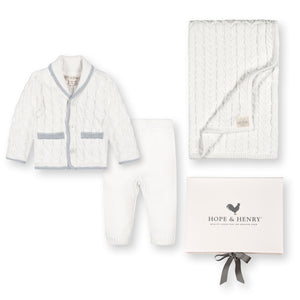 A cozy three-piece gift set featuring a white cable-knit cardigan with a shawl collar, matching leggings, and a soft blanket, all beautifully presented in a box from Hope & Henry.