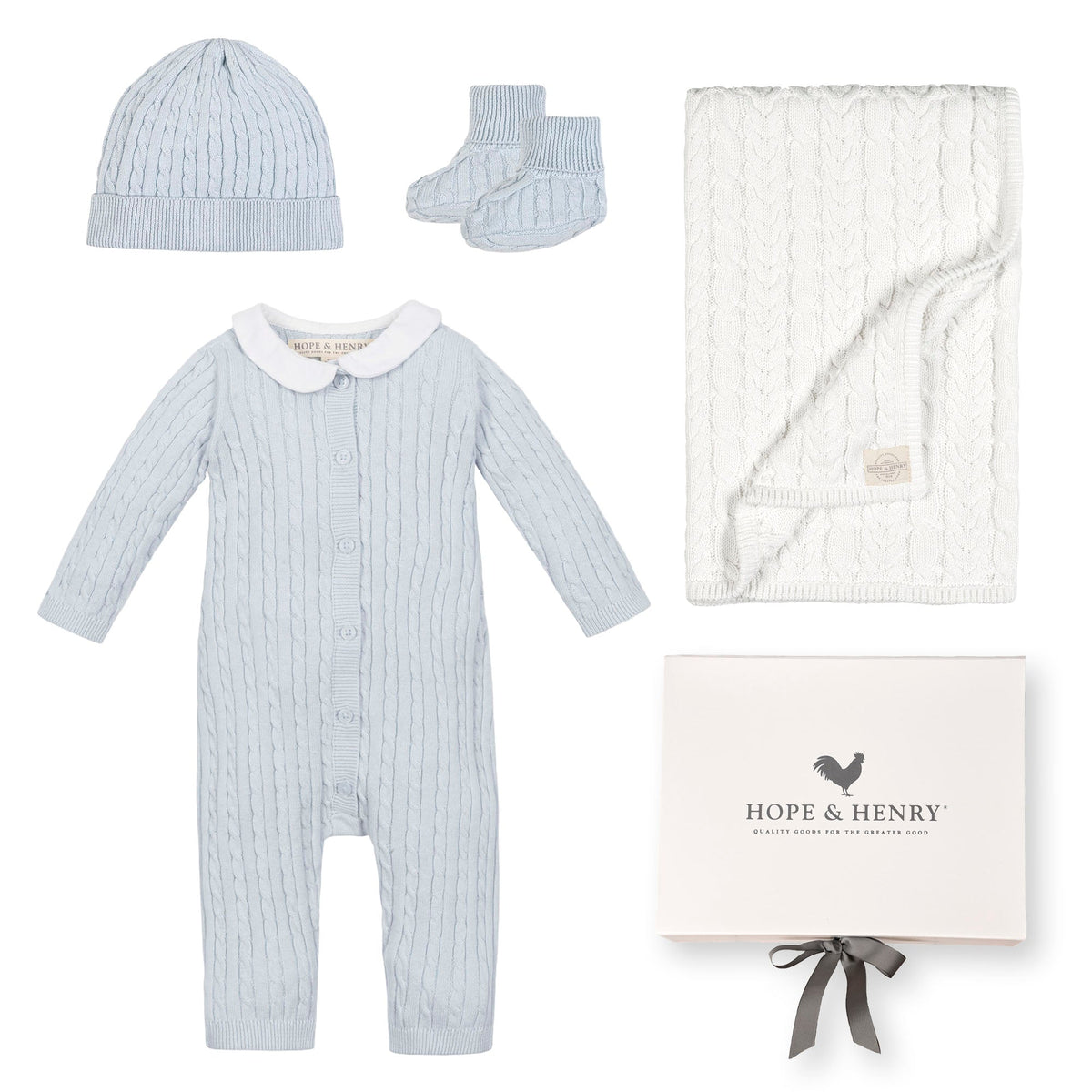 A pale blue baby romper with a Peter Pan collar, accompanied by a matching beanie, booties, and a white cable-knit blanket, all presented in a gift box by Hope &.