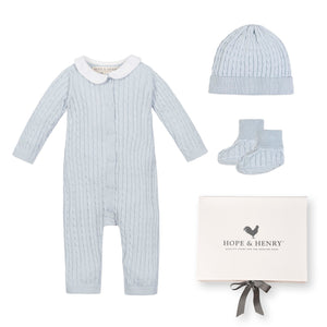 A pale blue baby romper with a Peter Pan collar is displayed alongside a matching beanie and booties, all neatly packaged in a gift box from Hope & Henry.