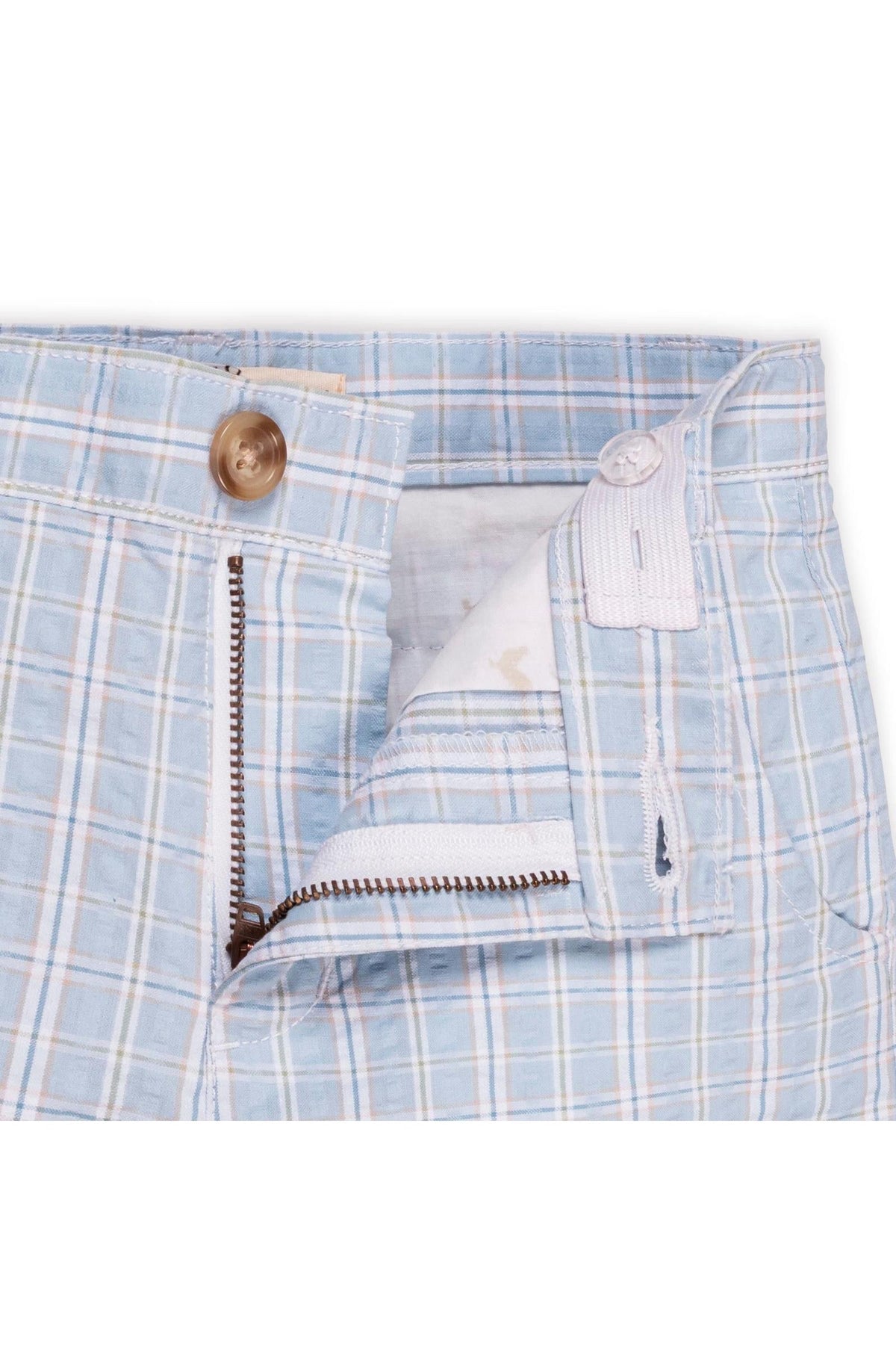 Close-up of blue and white checkered organic cotton seersucker shorts, featuring a faux horn button and zipper detail.