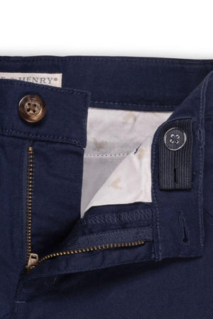 Close-up of navy linen shorts featuring a zipper, a faux tortoise button, and adjustable waistband details.