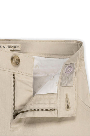 Close-up of Hope & Henry organic cotton shorts featuring a beige fabric, adjustable waistband, and faux tortoise button. The interior showcases a soft lining, emphasizing comfort and quality for kids.